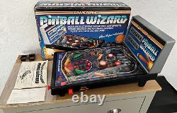 La traduction en français de ce titre est : 	 <br/>

'Flipper vintage Boxed Grandstand Pinball Wizard des années 1980 entièrement fonctionnel.'
