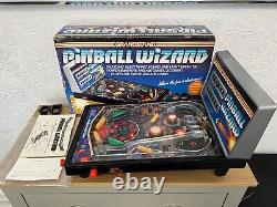 La traduction en français de ce titre est : <br/>'Flipper vintage Boxed Grandstand Pinball Wizard des années 1980 entièrement fonctionnel.'